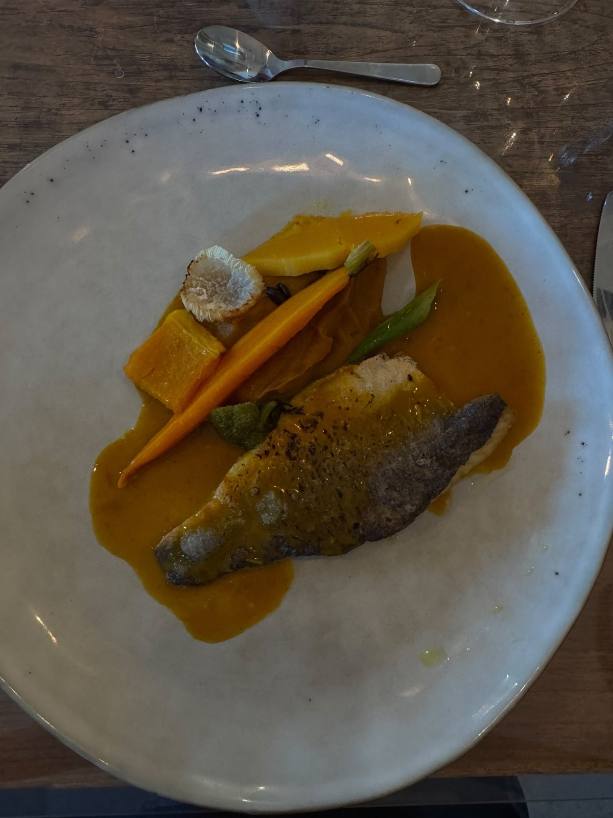 Een bord met vis, groenten en saus